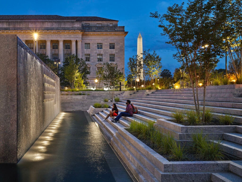 A Journey of Remembrance 3 A Journey of Remembrance By David Shiller | Stone steps provide contemplative seating at the memorial’s fountain. Submerged uplighting softens illumination of the inscribed wall. Photo: Alan Karchmer/OTTO