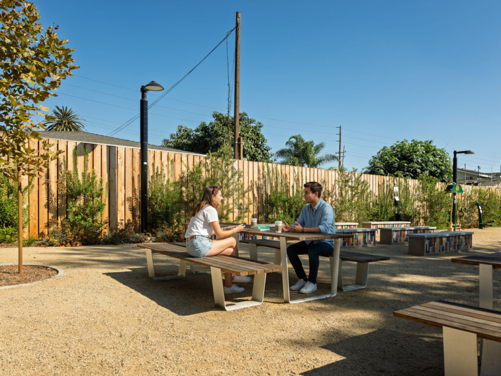 Alondra Gateway Park transforms a half-acre lot into a vibrant community destination | Two young people sitting and talking on a table